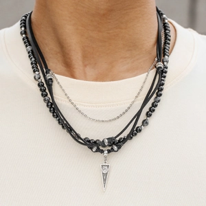 Detail van gelaagde lederen ketting met zwarte kralen en driehoekige hanger