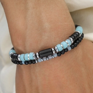 Dettaglio del bracciale a strati con turchese e perline di legno sul polso opaco