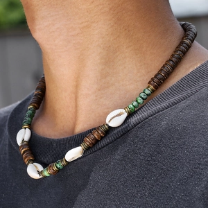 Dettaglio macro della collana boho da uomo con perle turchesi, cocco e conchiglie di ciprea