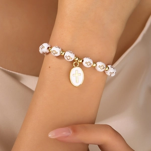 Primer plano de una pulsera religiosa de cuentas con colgante ovalado de cruz dorada