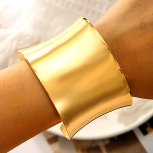 Close-up of minimalist wide gold open cuff bracelet with polished mirror finish for women