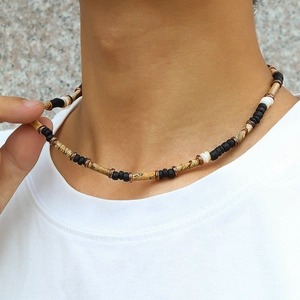 Detail einer Boho-Perlenkette mit Holzperlen und schwarzen Steinen auf weißem T-Shirt