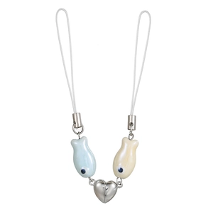 Detail of magnetic heart charm linking two ceramic fish pendants on a phone strap