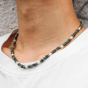Detail of beaded necklace featuring turquoise discs, faux pearls and brown coconut beads