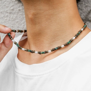 Close-up of beaded necklace featuring green turquoise, wood beads and pearls on neck