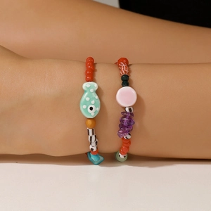 Détail de bracelets en perles avec poisson en céramique et pierres violettes