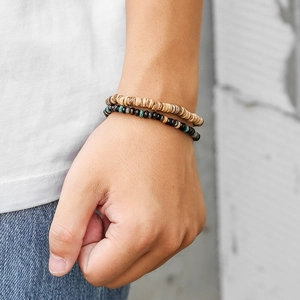 Nahaufnahme eines zweiteiligen Armband-Sets aus Naturholzperlen am Handgelenk