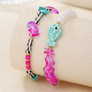 Détail de bracelets perlés avec poissons en céramique et perles sur support de bijoux