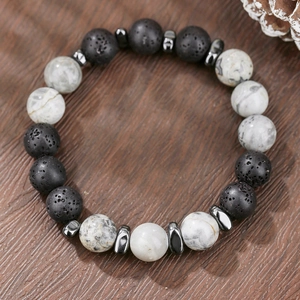 Detailed macro view of black volcanic lava beads and white marble stones on a wooden background