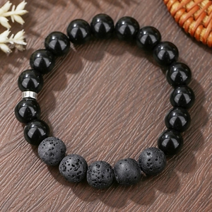 Macro detail of obsidian and lava stone beads with a silver metal cylinder spacer