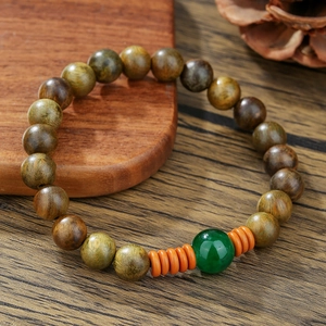 Bracelet vintage en perles de bois avec agate verte et espaceurs orange sur bois rustique