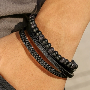 Detalle de pulsera multicapa negra para hombre con cuentas mate y cuero trenzado