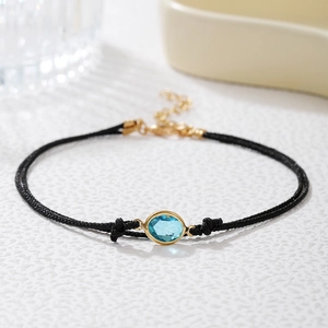 Tobillera minimalista de doble cordón negro con circonita azul y cierre chapado en oro