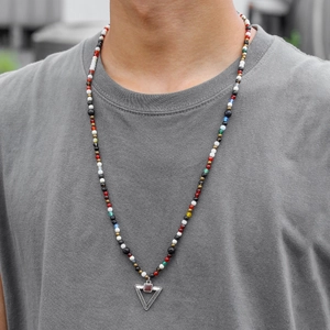 Detailed shot of multi-colored beaded necklace with silver triangle pendant on a model