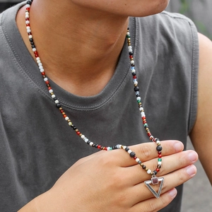 Detail of colorful beaded necklace with a geometric triangle pendant and red stone inlay