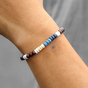 Detail van een boho-armband van kokosnoot en hout met gemengde texturen om de pols