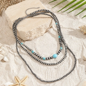 Detail van Boheemse gelaagde ketting met turquoise kralen op een strandstijl achtergrond