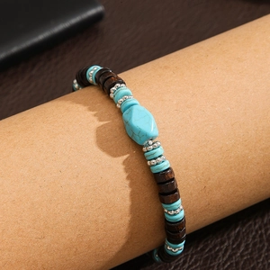 Detalle de pulsera étnica con piedras turquesas y cuentas de madera en un tubo