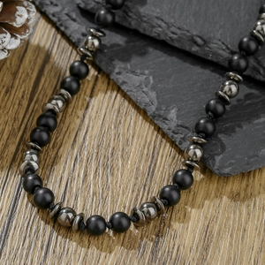 Collier pour hommes en perles noires mates et hématite sur un fond naturel rustique