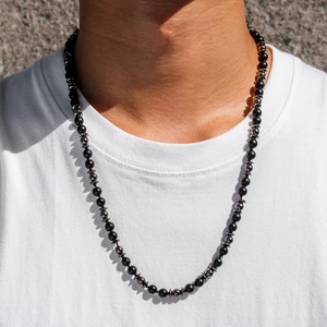 Gros plan de perles noires mates pour hommes et de pierres d'hématite sur un long collier