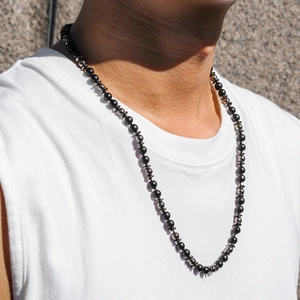 Détail d'un collier pour homme avec perles noires mates et intercalaires en métal argenté
