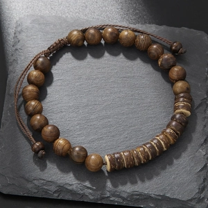 Detalle de pulsera de cuentas de madera con piezas de coco sobre piedra negra