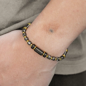 Detailed view of beaded bracelet with black tiger eye stone and golden metal accents