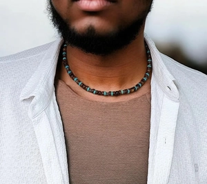 Détail d'un collier ras du cou pour homme en perles de bois brun et touches de turquoise
