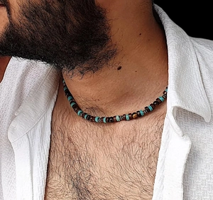 Gros plan sur collier homme avec perles en bois marron et touches de turquoise