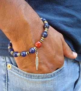 Close-up of blue lapis lazuli beaded bracelet with a silver feather pendant on wrist