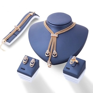 Détails d'une parure dorée ornée de cristaux sur un présentoir à bijoux bleu marine