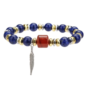 Close-up of blue lapis stone bracelet with red jasper bead and silver feather charm
