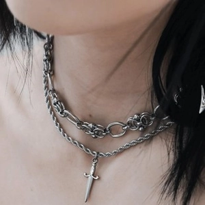 Gros plan d'un collier double épaisseur argenté avec un pendentif poignard de style gothique