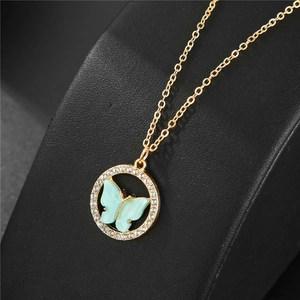 Détail d'un collier papillon doré serti de cristaux sur support en cuir noir élégant