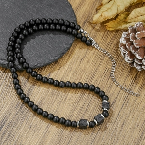Men's beaded necklace with black lava stones and stainless steel clasp on wood