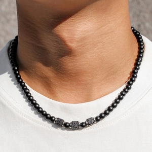 Macro detail of black matte beads and square lava stones on a men's beaded necklace