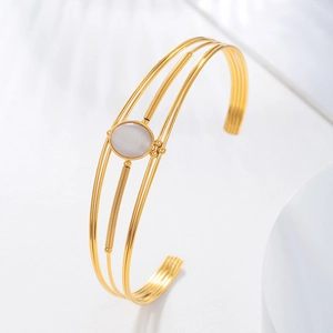 Detail of gold minimalist open bangle featuring four sleek wires and a round gemstone inlay