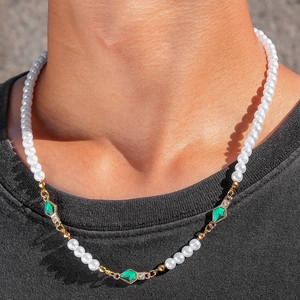 Detailed view of pearl and green crystal necklace on a neck with gold-plated metal accents