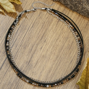 Retro multi-layer black onyx and leather chain necklace displayed on rustic wood