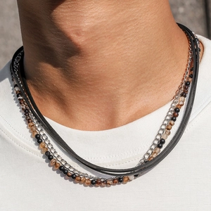 Close-up of layered necklace with black leather cord, silver chain, and multi-color beads