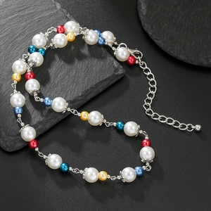 Multicolor pearl beaded necklace with silver lobster clasp on a black textured stone surface