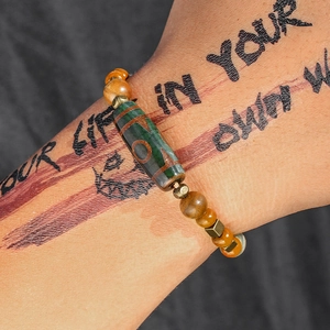 Detail eines tibetischen Dzi-Perlenarmbands mit Tigerauge-Holzperlen am Handgelenk