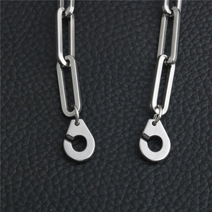 Macro detail of industrial stainless steel link chain with unique handcuff charm on leather