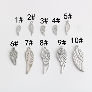 Gros plan de pendentifs ailes et plumes en acier inoxydable pour création de bijoux