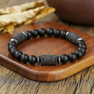 Herenarmband met matzwarte kralen en cilindrische lavastenen op een houten dienblad