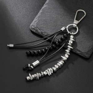 Industrial style keychain featuring black beads and metallic geometric charms on rock