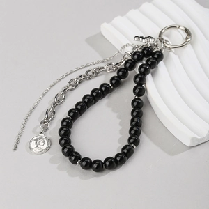 Detail of punk style keychain with black beads, silver chains and a cross pendant
