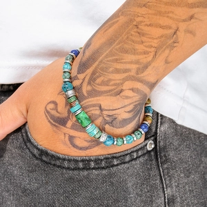 Detailed close-up of handmade boho turquoise beaded bracelet on wrist with tattoos
