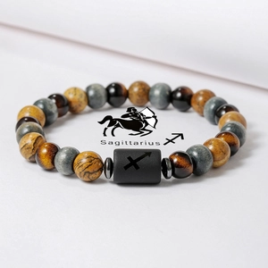 Vista macro de pulsera Sagitario de piedras naturales con ojo de tigre y dije grabado