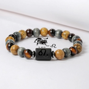 Detalle macro de la pulsera del zodiaco Leo con cuentas de ojo de tigre y dije grabado